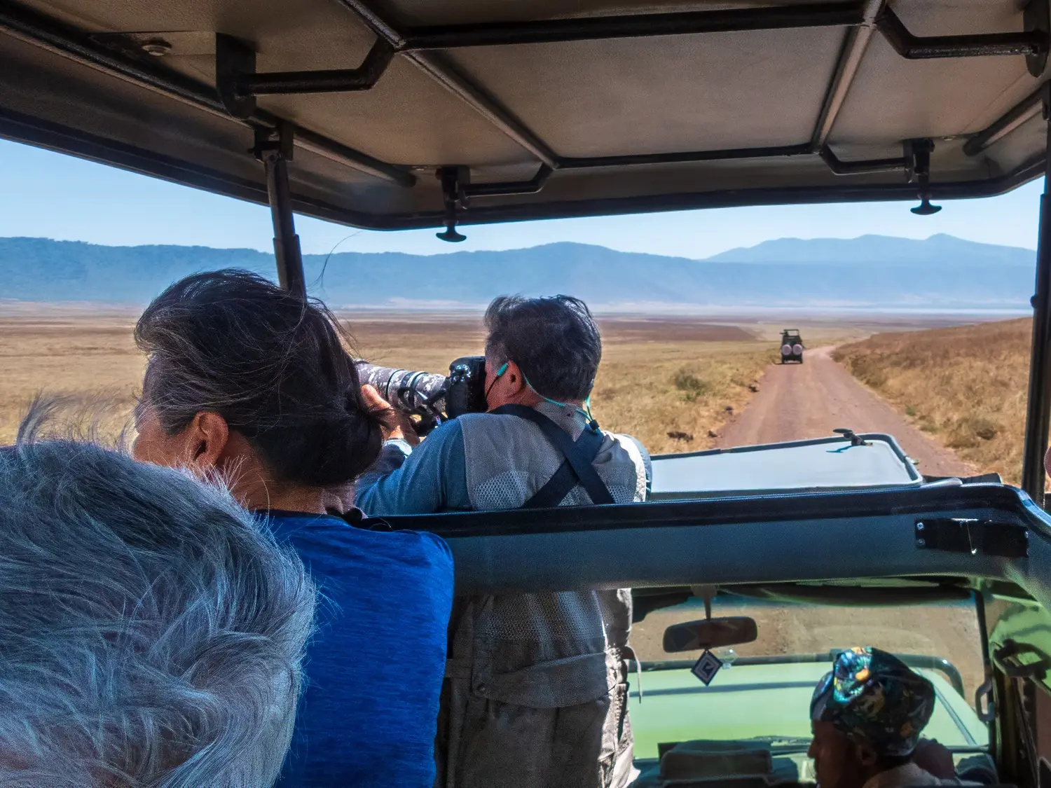 Guests photographing wildlife from an open roof safari vehicle in Ngorongoro Crater